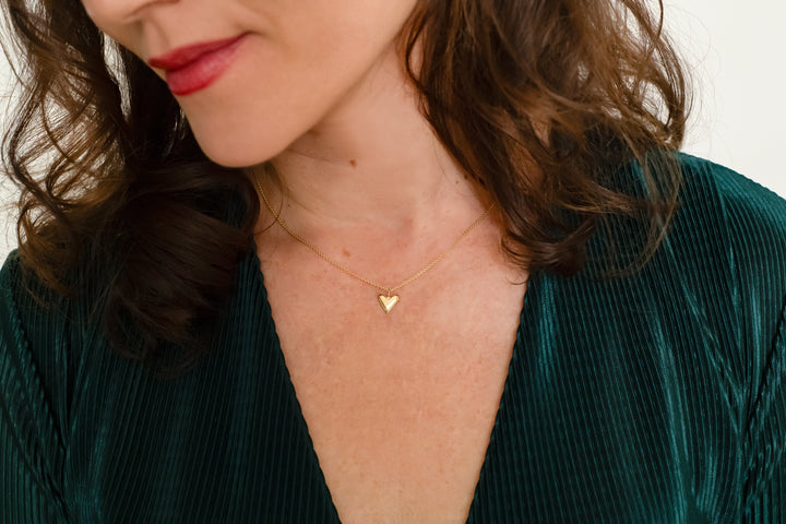 Vrouw met gouden collier met hartje. Geelgoud 14 karaat, verfijnd sieraad.