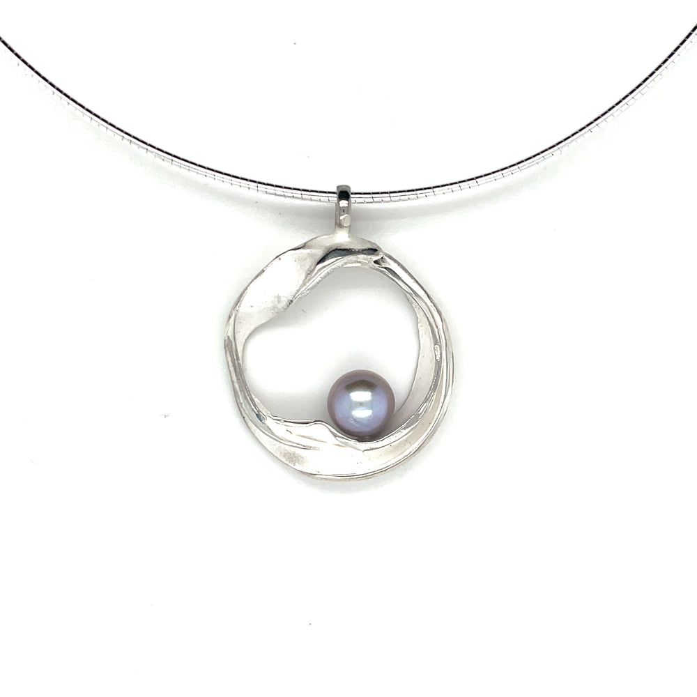 Handgemaakte zilveren hanger met grijze parel, ontworpen en gemaakt door Lianne de Witte in haar atelier in Goes, gemaakt in cirkelvorm.