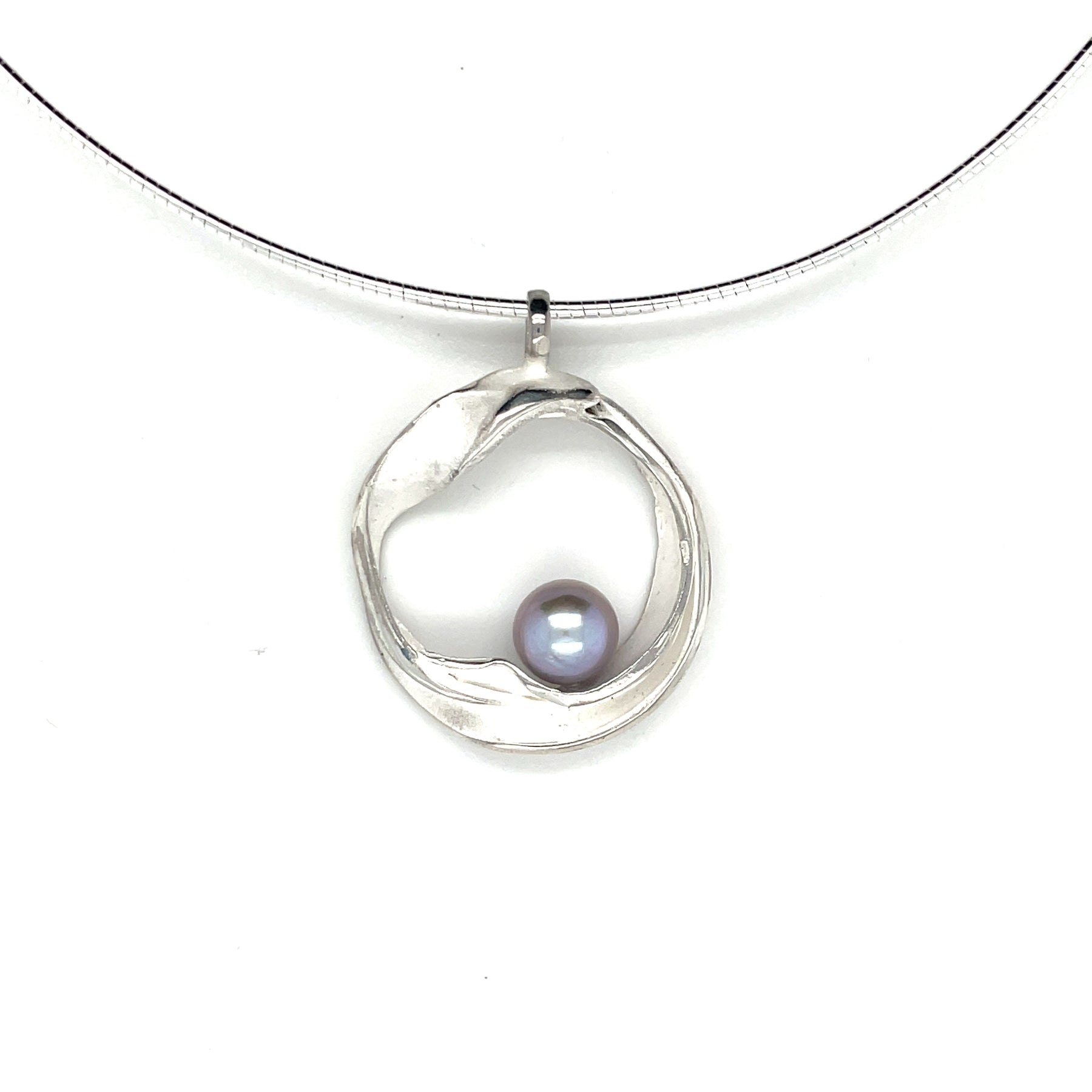 Handgemaakte zilveren hanger met grijze parel, ontworpen en gemaakt door Lianne de Witte in haar atelier in Goes, gemaakt in cirkelvorm.