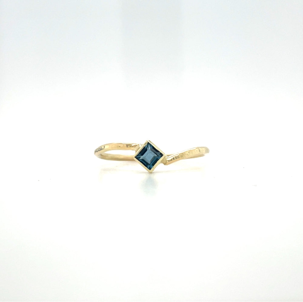 Geelgouden ring met hamerslag, speels ontwerp, handgemaakt door Lianne de Witte en heeft een vierkante londen blue topaas.
