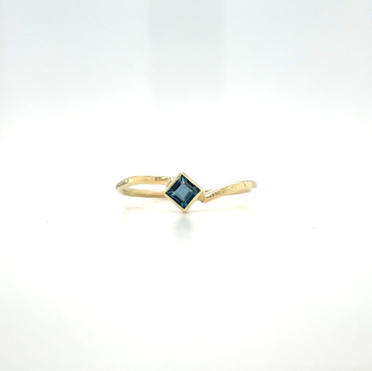 Geelgouden ring met hamerslag, speels ontwerp, handgemaakt door Lianne de Witte en heeft een vierkante londen blue topaas.