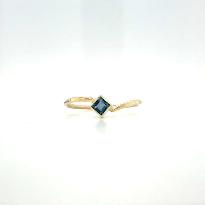 Geelgouden ring met hamerslag, speels ontwerp, handgemaakt door Lianne de Witte en heeft een vierkante londen blue topaas.