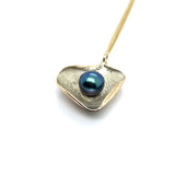 Zijaanzicht van handgemaakte hanger van 14 karaat geelgoud met zoetwater parel zwart/groen, ontworpen en gemaakt door Lianne de Witte in haar atelier in Goes