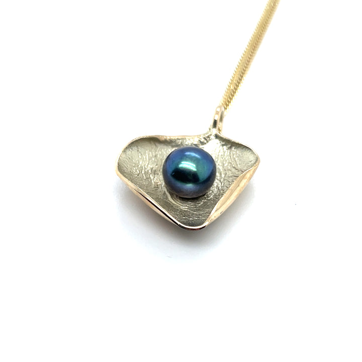 Zijaanzicht van handgemaakte hanger van 14 karaat geelgoud met zoetwater parel zwart/groen, ontworpen en gemaakt door Lianne de Witte in haar atelier in Goes