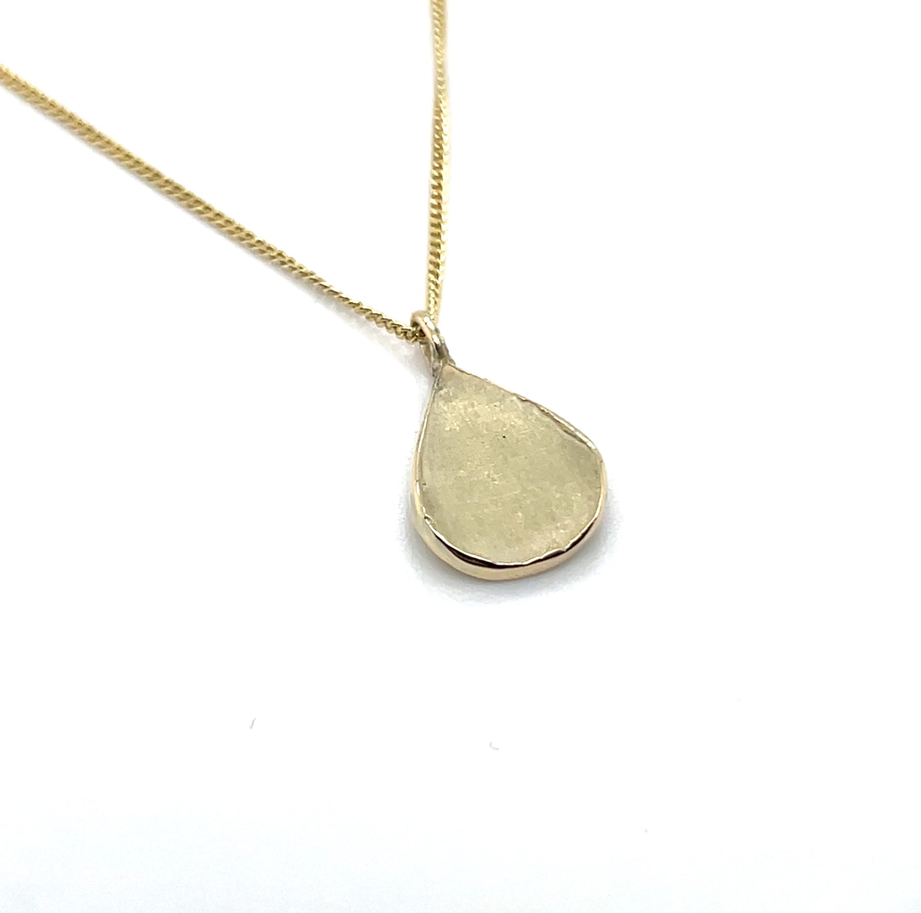 Close up van handgemaakte kleine hanger van 14 karaat geelgoud, ontworpen en gemaakt door Lianne de Witte in haar atelier in Goes