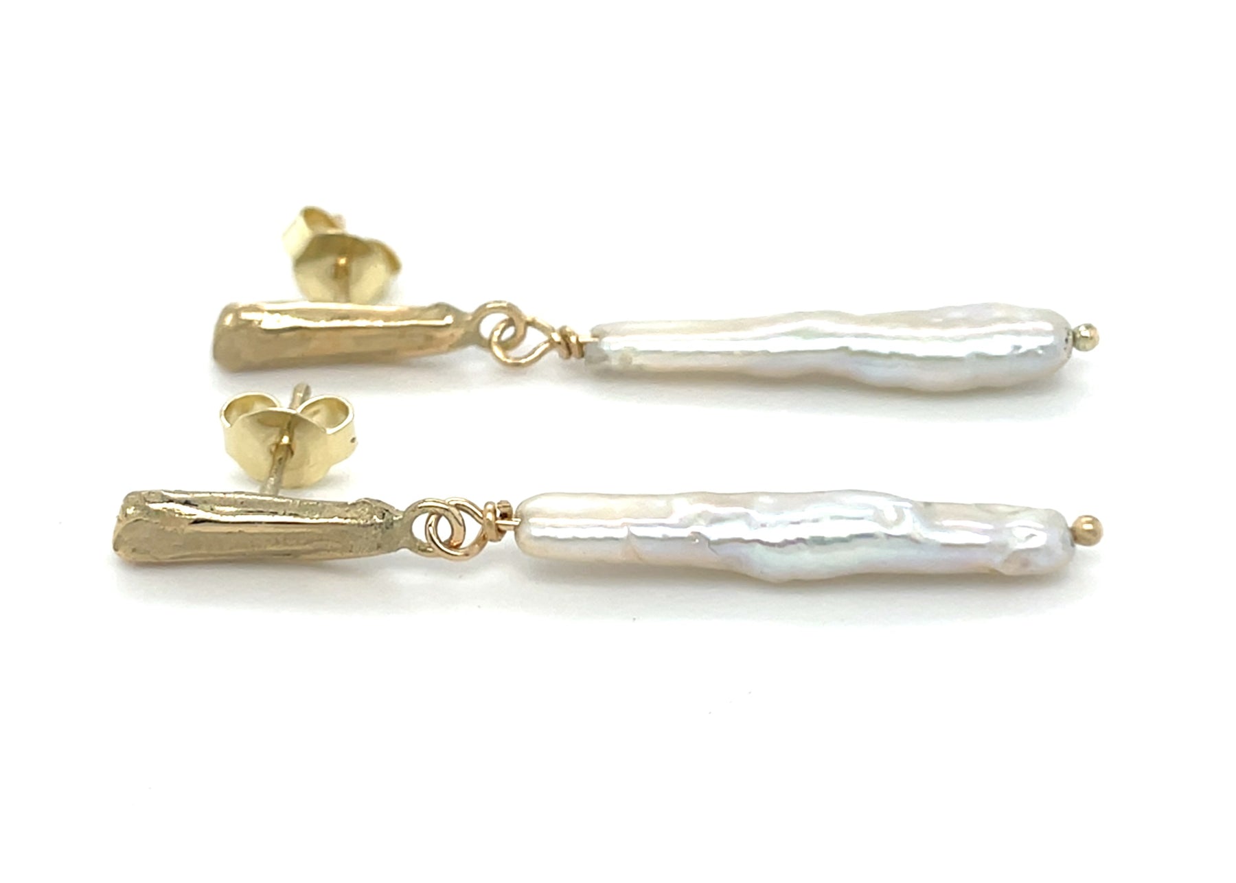 Zijaanzicht van handgemaakte oorhanger van 14 karaat geelgoud met zoetwaterparel wit, ontworpen en gemaakt door Lianne de Witte in haar atelier in Goes.