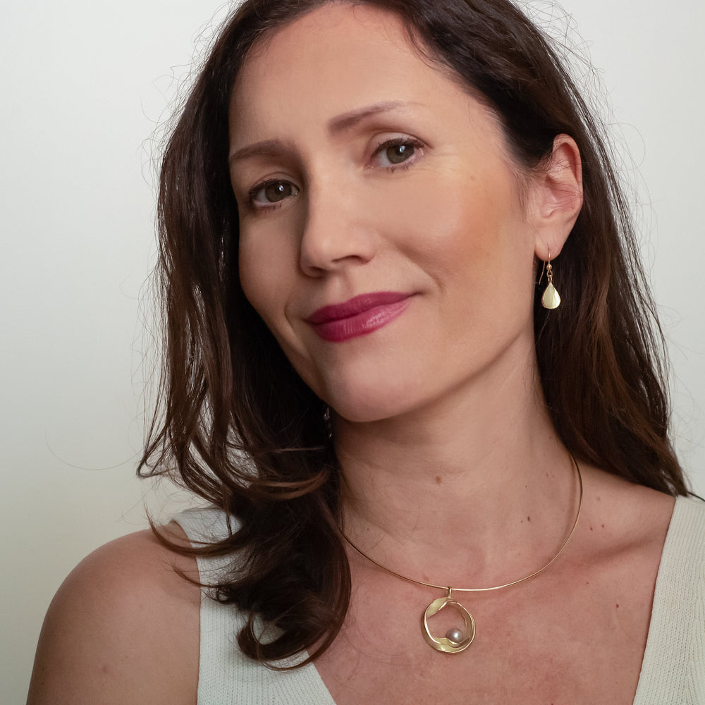 Mooie model foto met gouden hanger en grijze parel.