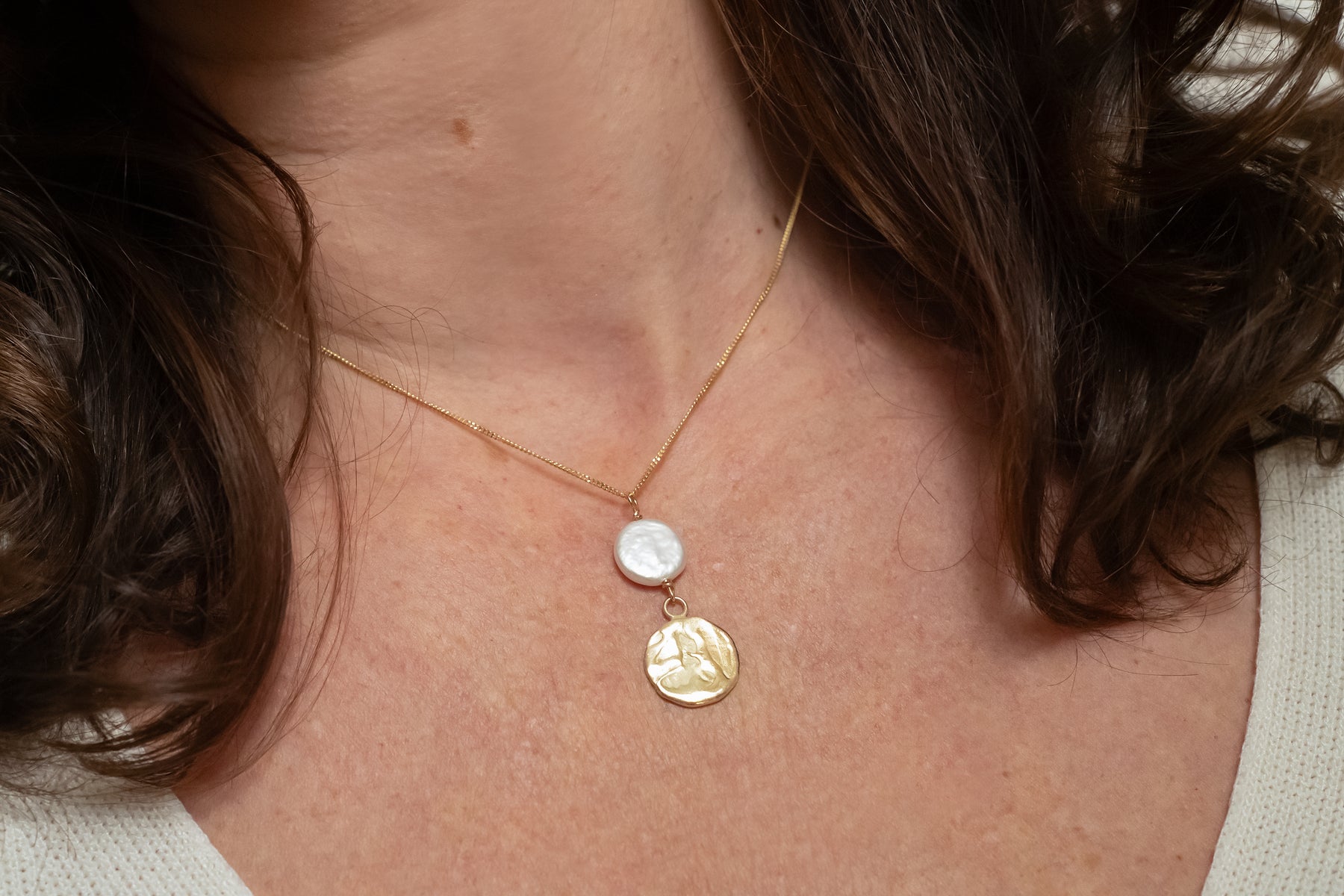 Close up van handgemaakte hanger van 14 karaat geelgoud met zoetwaterparel wit, ontworpen en gemaakt door Lianne de Witte in haar atelier in Goes.